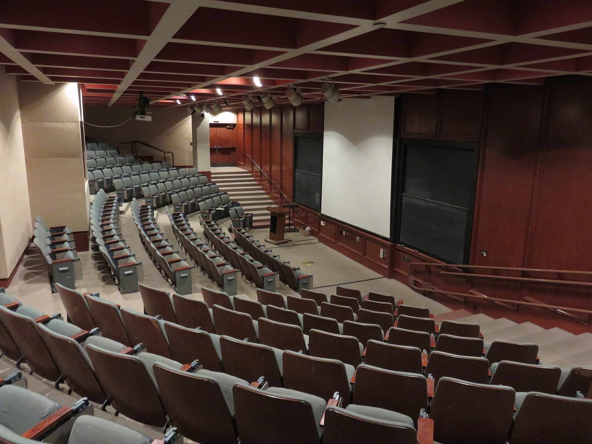 Rows of empty seats in a tiered university lecture hall, from the Trevor L Taylor cluster on education access and scholarships