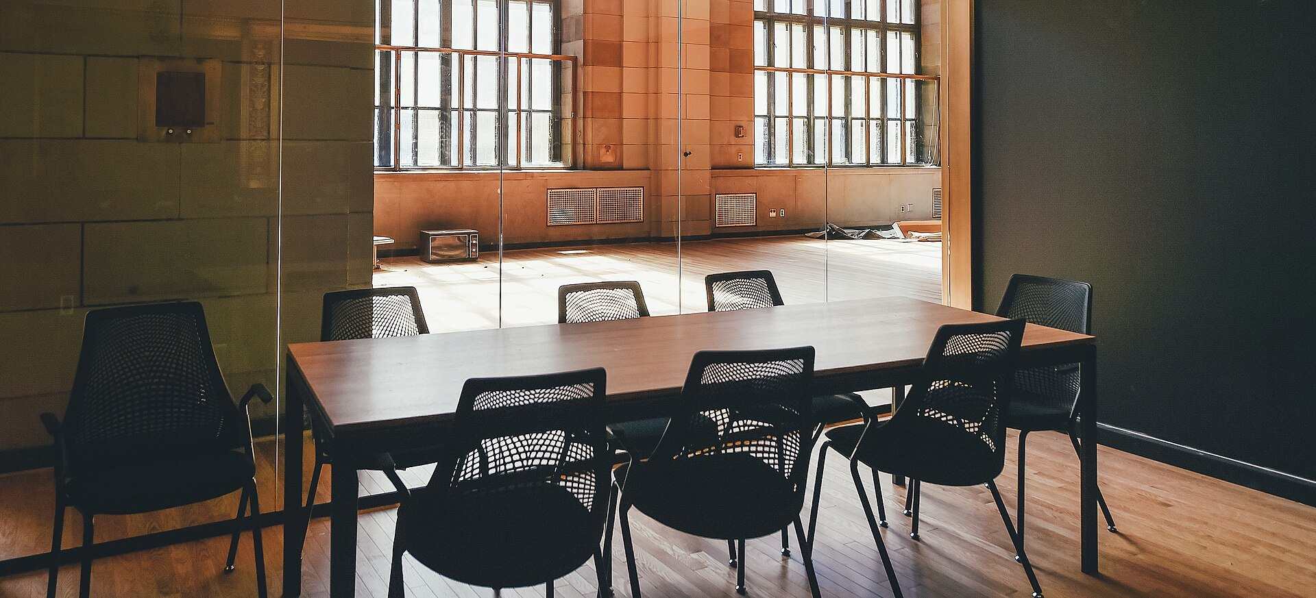 A small meeting table with black mesh chairs behind a glass wall in a sunlit stone building, from the Trevor L Taylor entry on coinvestment