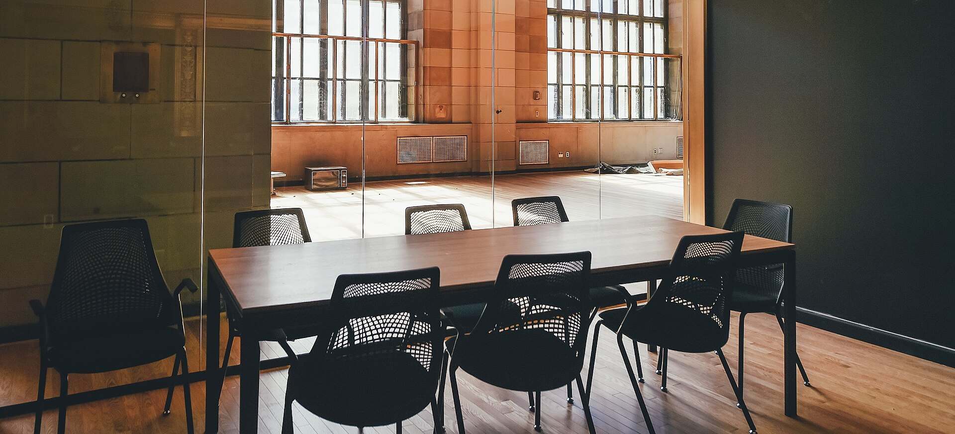 A small meeting table with black mesh chairs behind a glass wall in a sunlit stone building, from the Trevor L Taylor entry on coinvestment