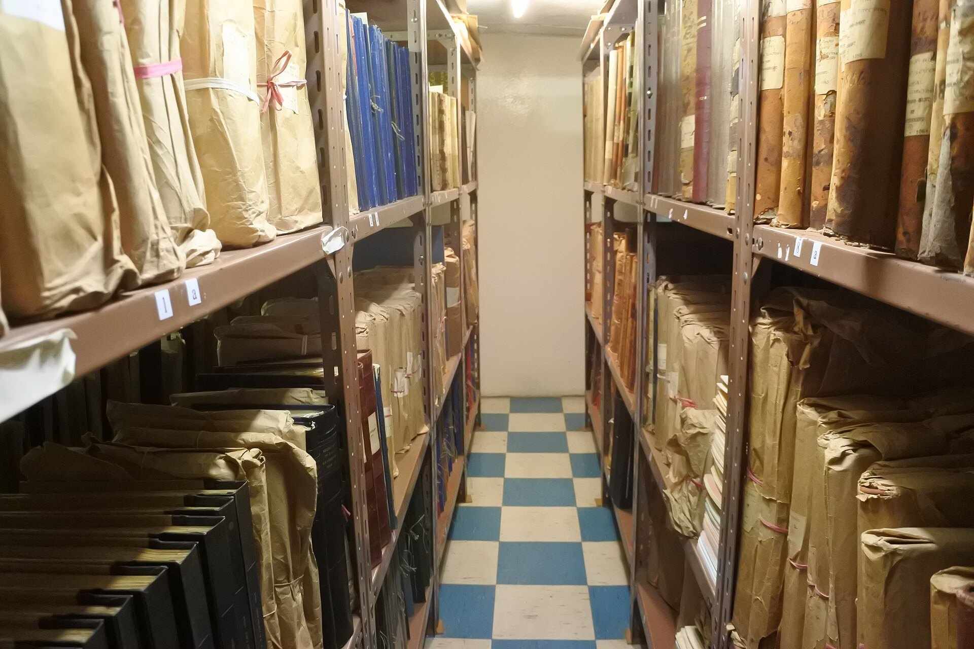 An archive aisle lined with shelves of bound records, from the Trevor L Taylor references page