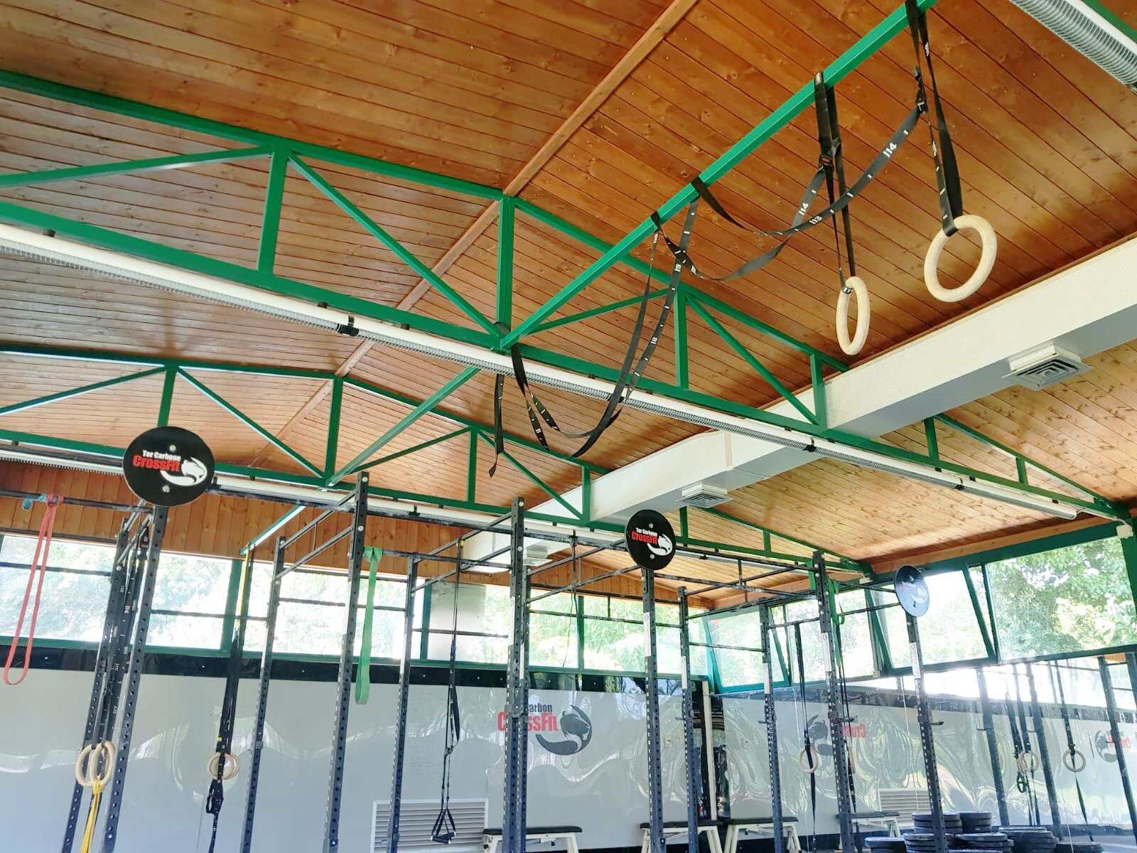 Gymnastic rings and pull up rigs under a wooden roof in an empty CrossFit gym, from the Trevor L Taylor entry on CrossFit