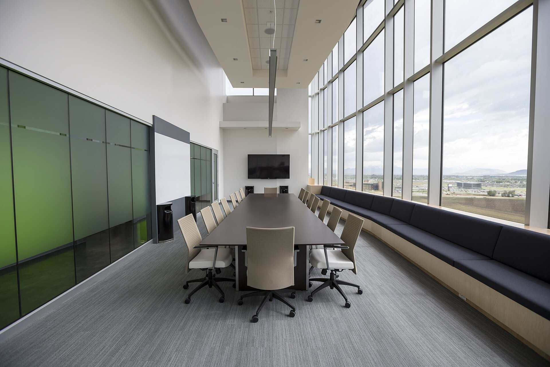 An empty boardroom with a long table, white chairs and a wall of tall windows, illustrating the Trevor L Taylor entry on the family office