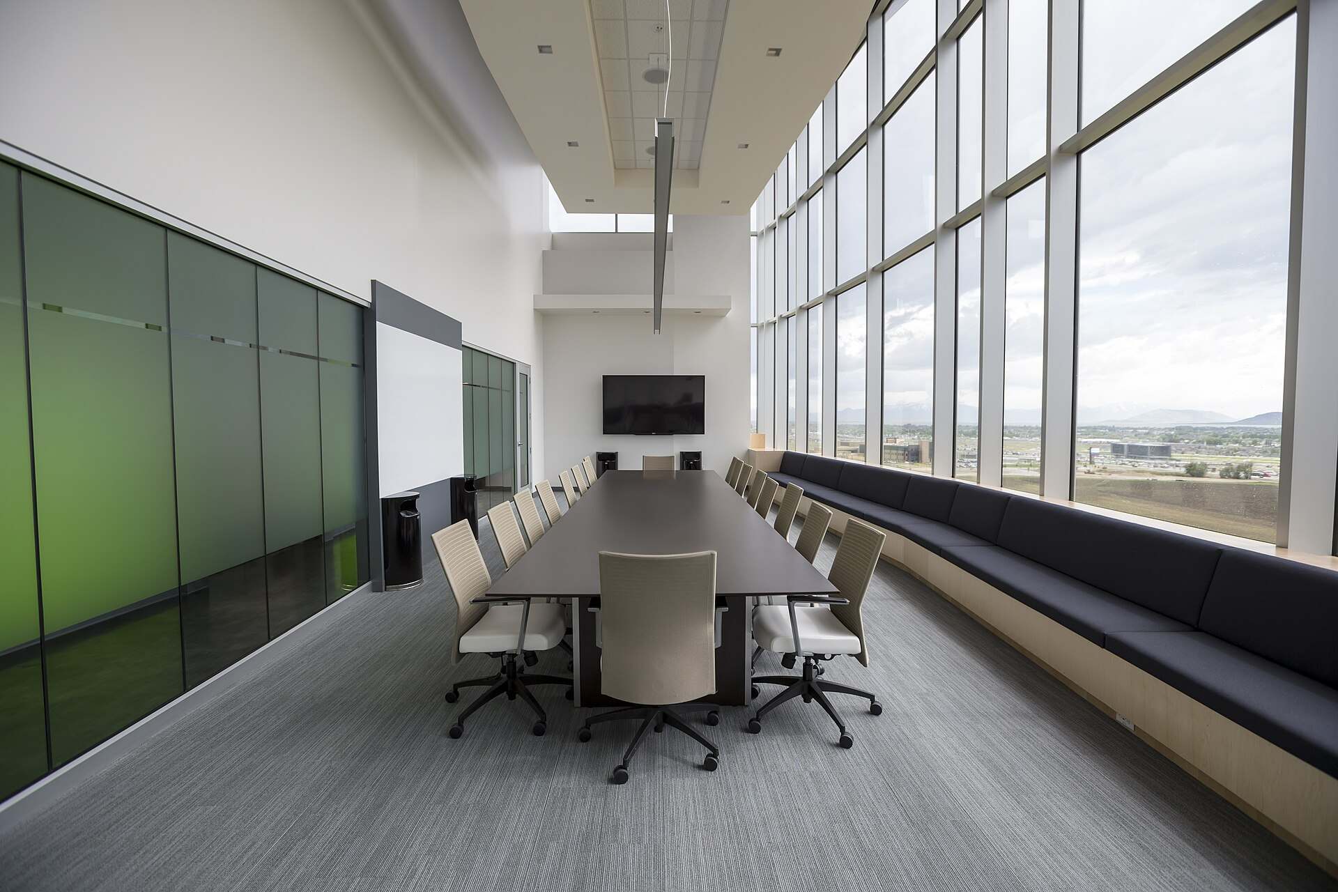 An empty boardroom with a long table, white chairs and a wall of tall windows, illustrating the Trevor L Taylor entry on the family office