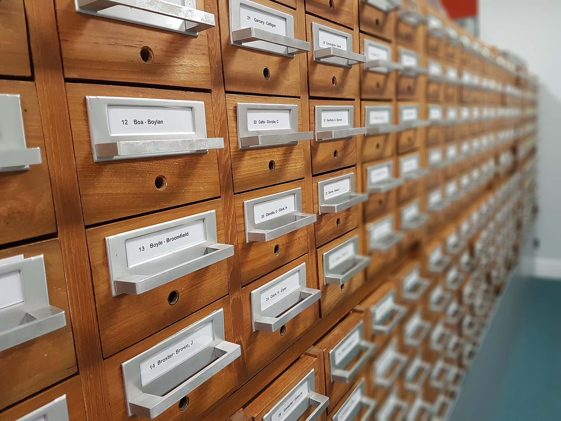 Wooden card catalog with rows of labeled metal drawer pulls receding into the distance, from the Trevor L Taylor entry on due diligence
