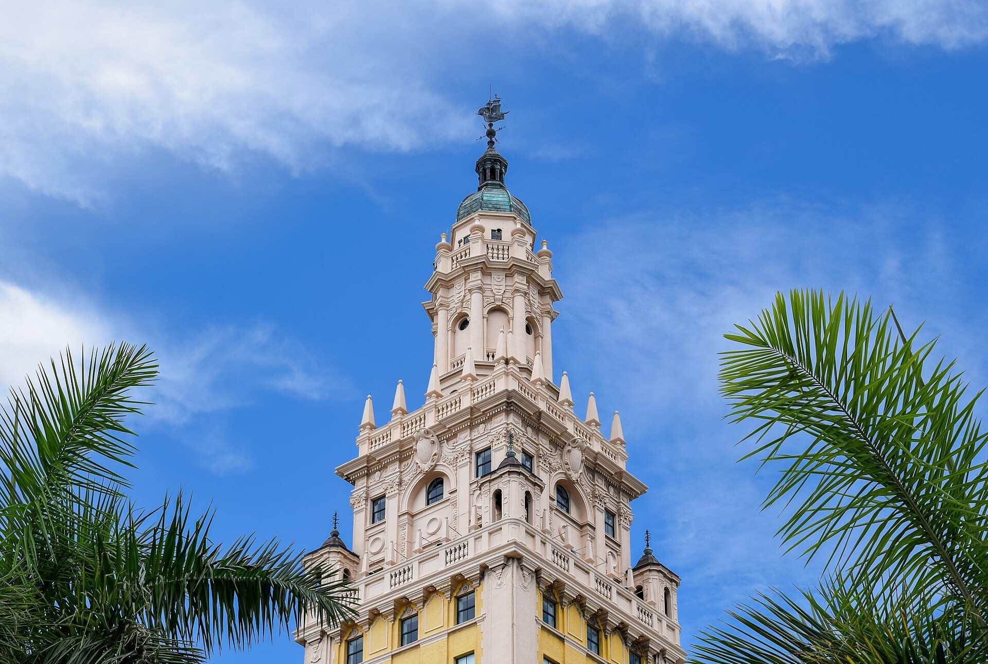 The ornate cupola of the Freedom Tower in Downtown Miami framed by palm fronds, from the Trevor L Taylor entry on Miami as a gateway to Latin America