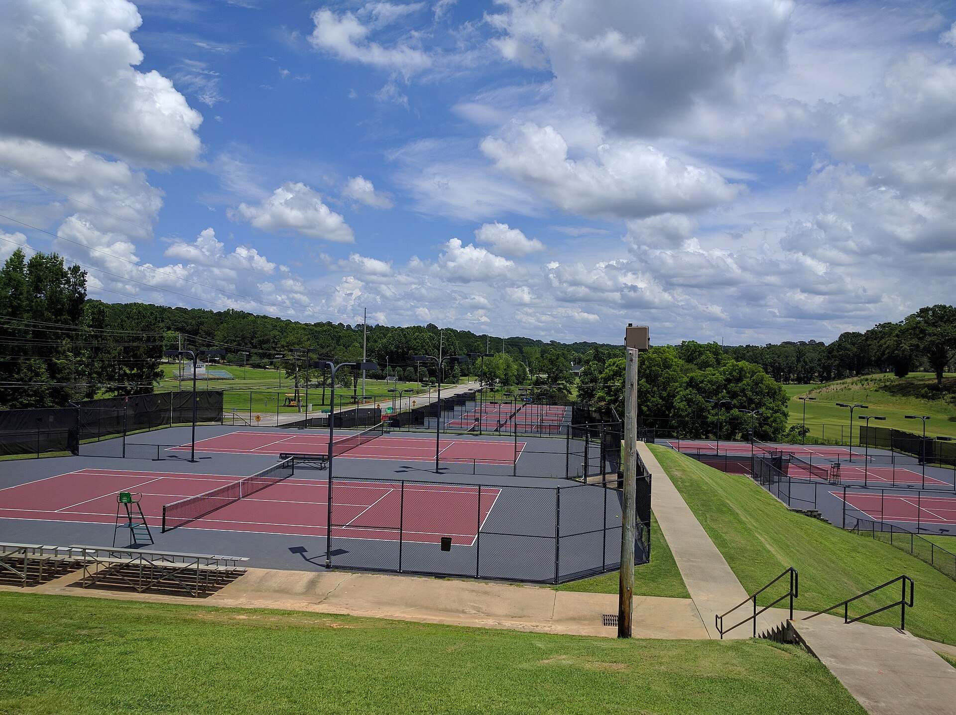 Rows of college tennis playing surfaces under a summer sky at a campus complex in Alabama, from the Trevor L Taylor entry on NCAA Division I tennis