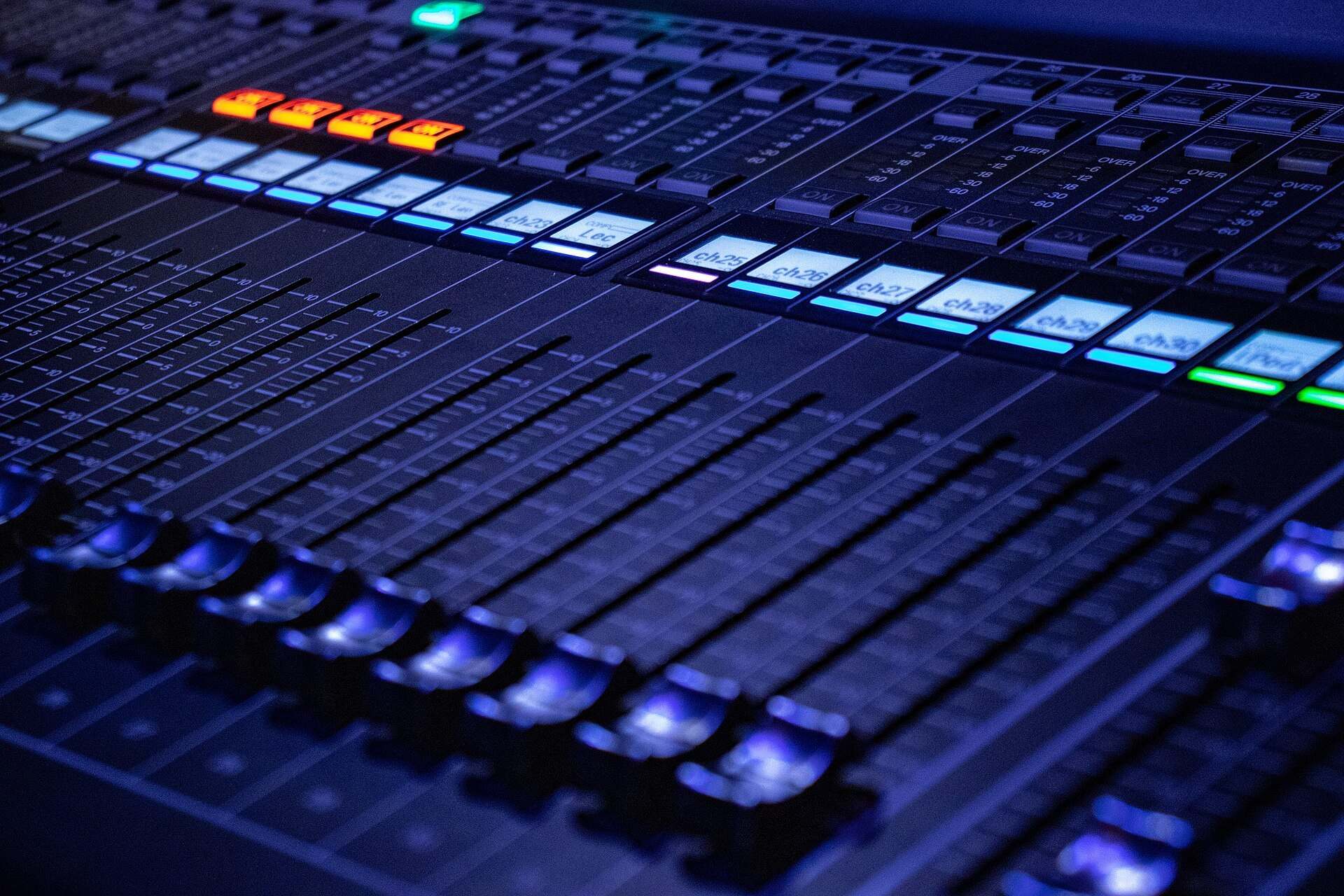 Close view of lit channel faders and level displays on a digital audio mixing console, from the Trevor L Taylor entry on podcast audience measurement