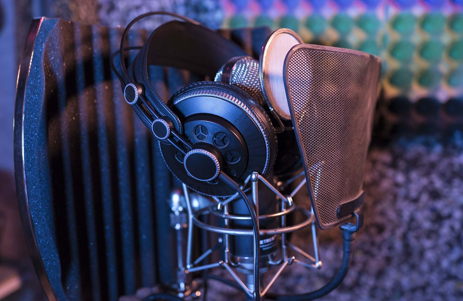 Studio headphones hung over a condenser microphone with a pop filter in a padded booth, from the Trevor L Taylor entry on podcast platforms