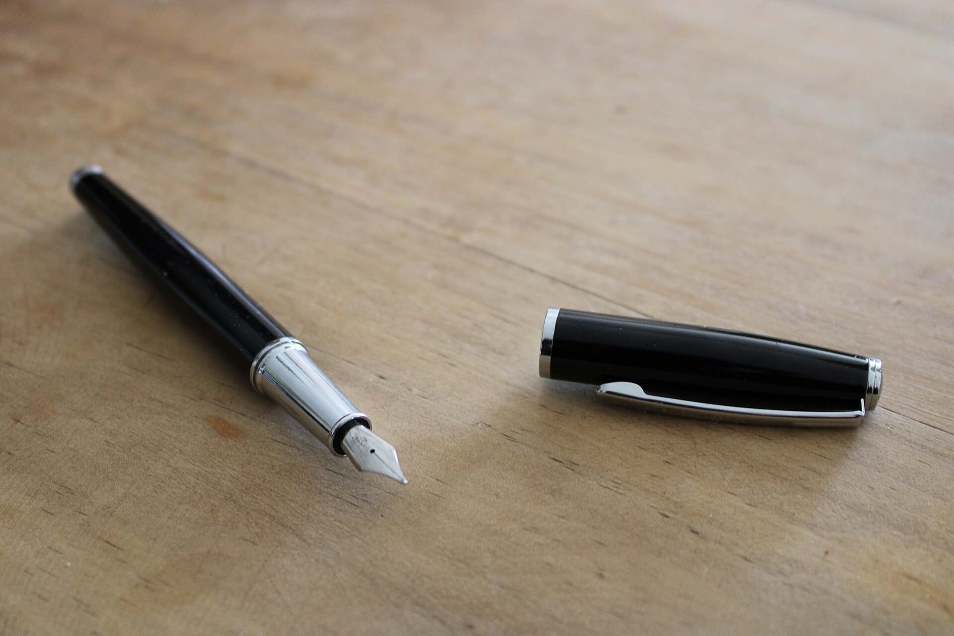 Uncapped black fountain pen and its cap resting on a wooden desk, from the Trevor L Taylor entry on reading a private deal memo