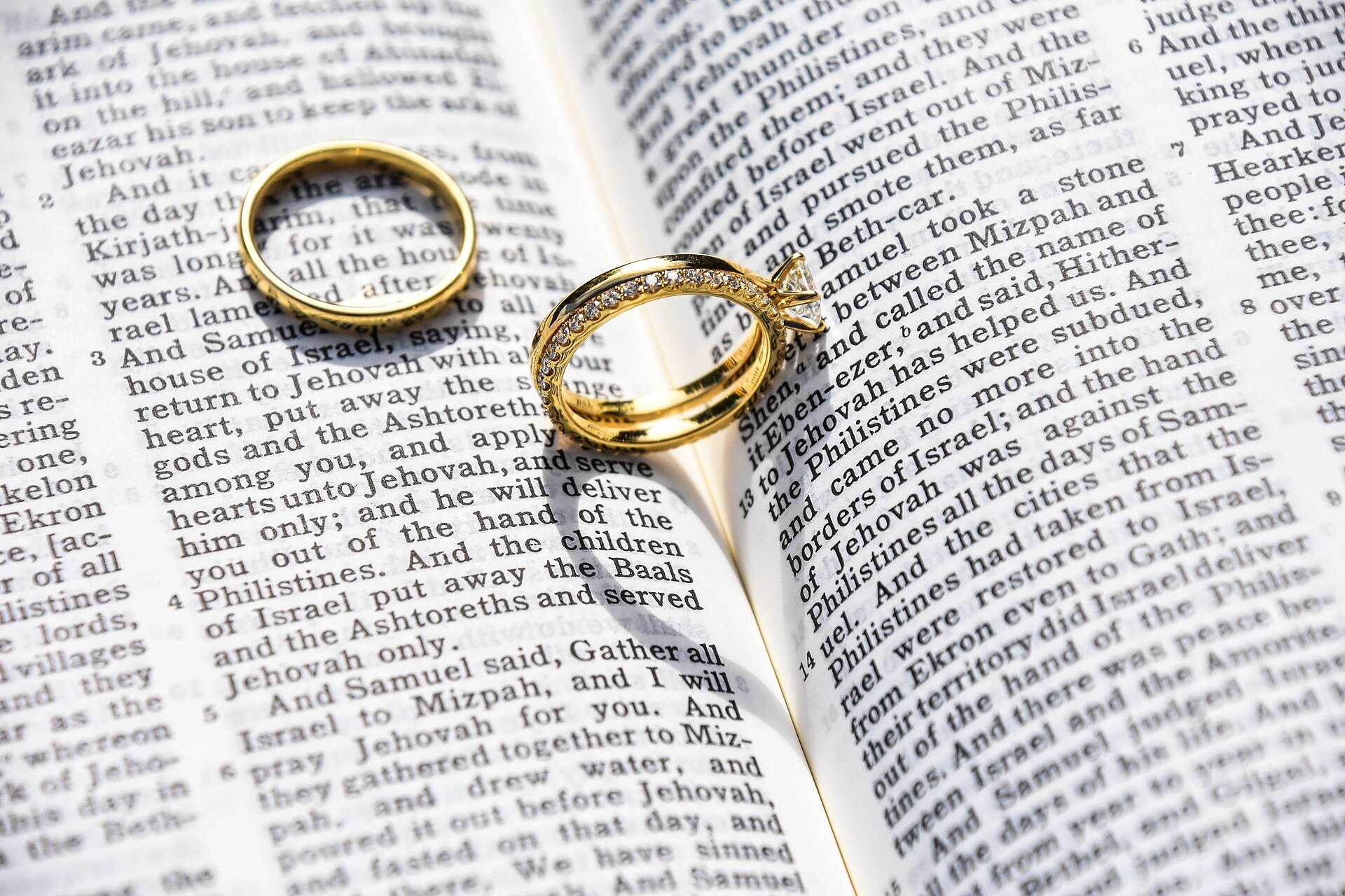 Two gold wedding rings resting on the pages of an open book, illustrating a Trevor L Taylor podcast episode on attraction and lasting love