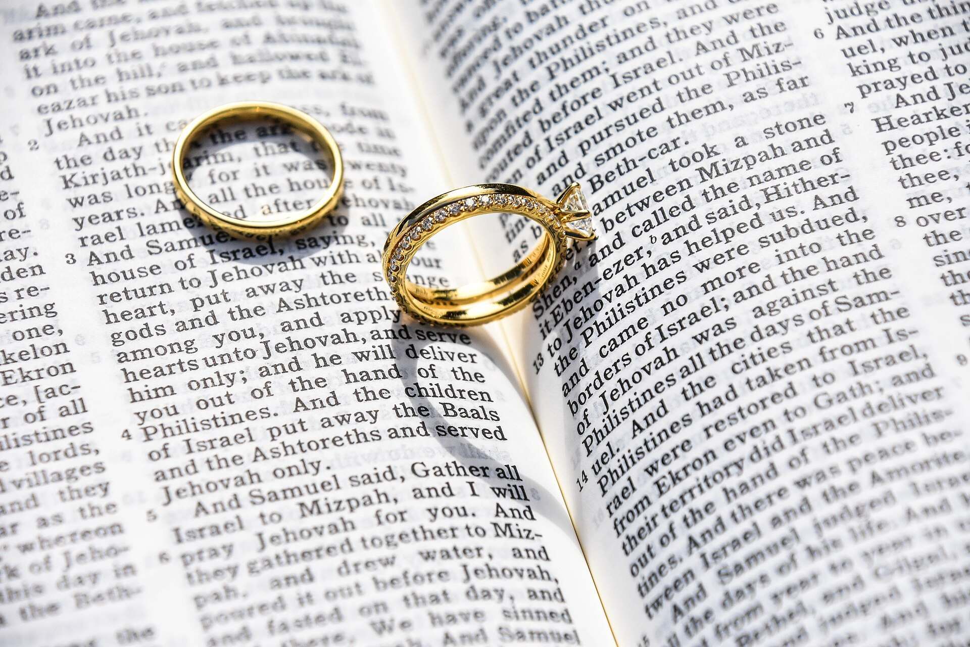 Two gold wedding rings resting on the pages of an open book, illustrating a Trevor L Taylor podcast episode on attraction and lasting love