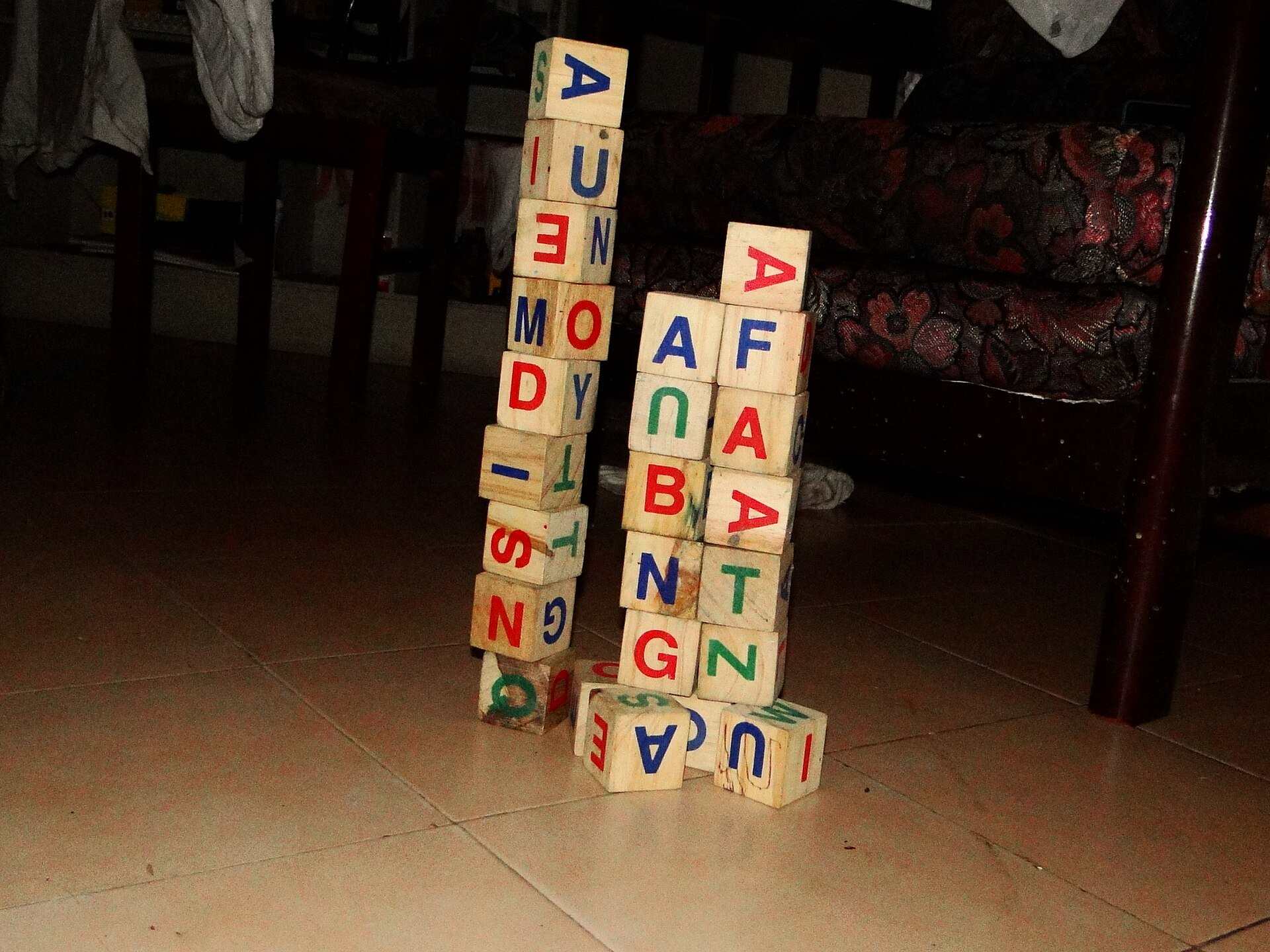 Stacked wooden alphabet blocks on a floor, illustrating a Trevor L Taylor podcast episode on early screen time and young brains