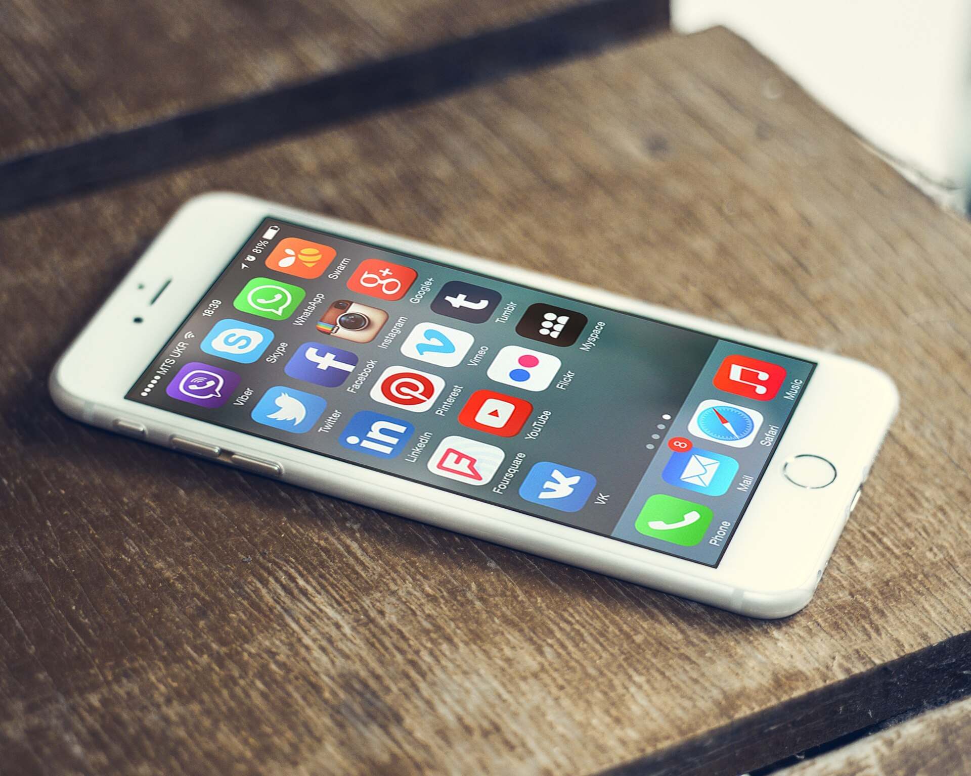 A smartphone showing social media app icons on a wooden table, illustrating a Trevor L Taylor podcast episode on digital dopamine