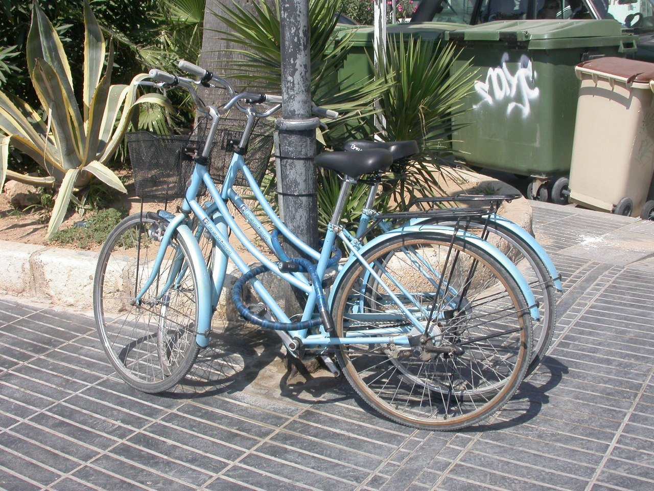 Two pale blue bicycles locked together against a post, illustrating a Trevor L Taylor podcast episode on shared effort in a partnership