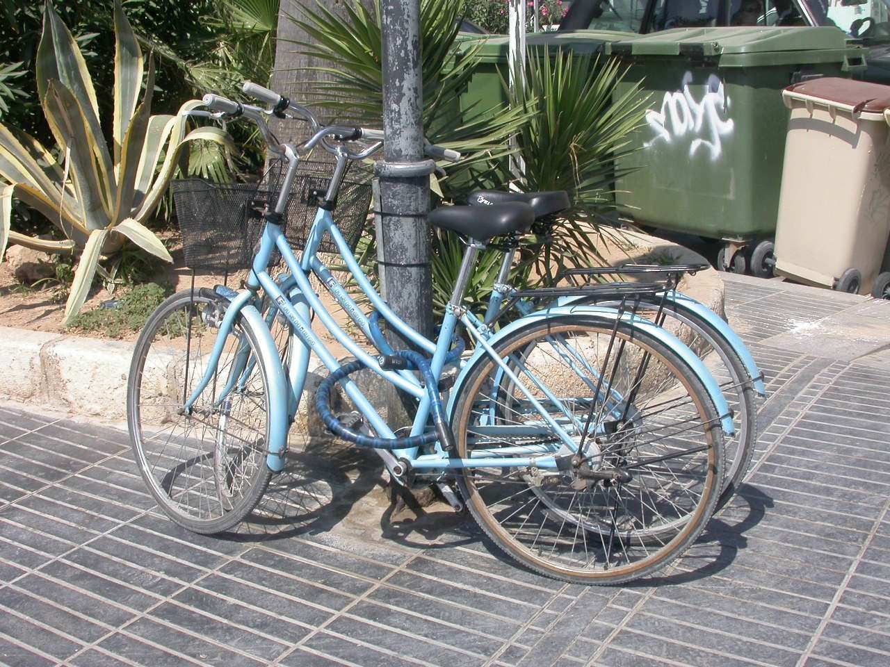 Two pale blue bicycles locked together against a post, illustrating a Trevor L Taylor podcast episode on shared effort in a partnership