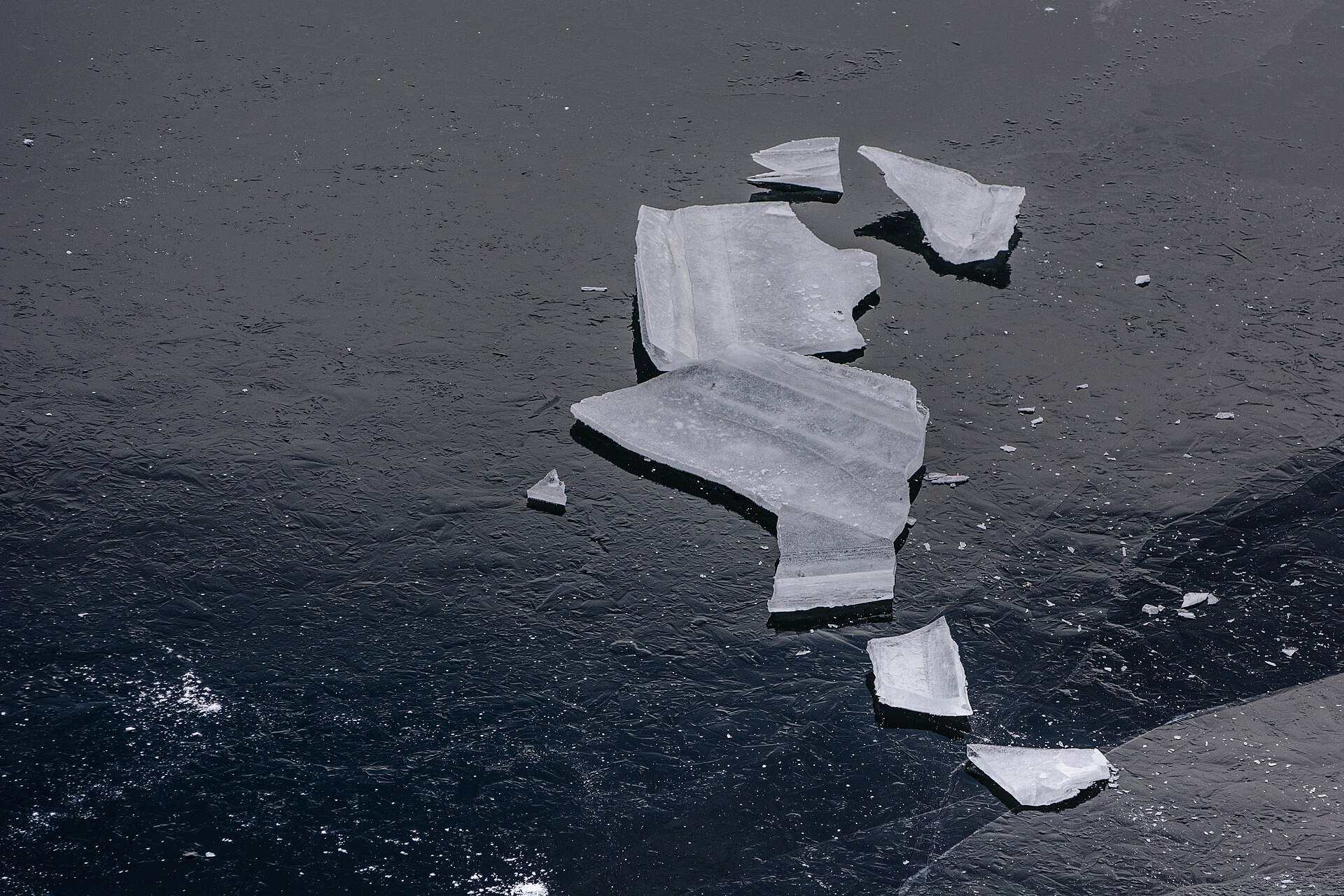 Broken pieces of ice lying on a dark frozen lake, illustrating a Trevor L Taylor podcast episode on adaptation to habitual stress