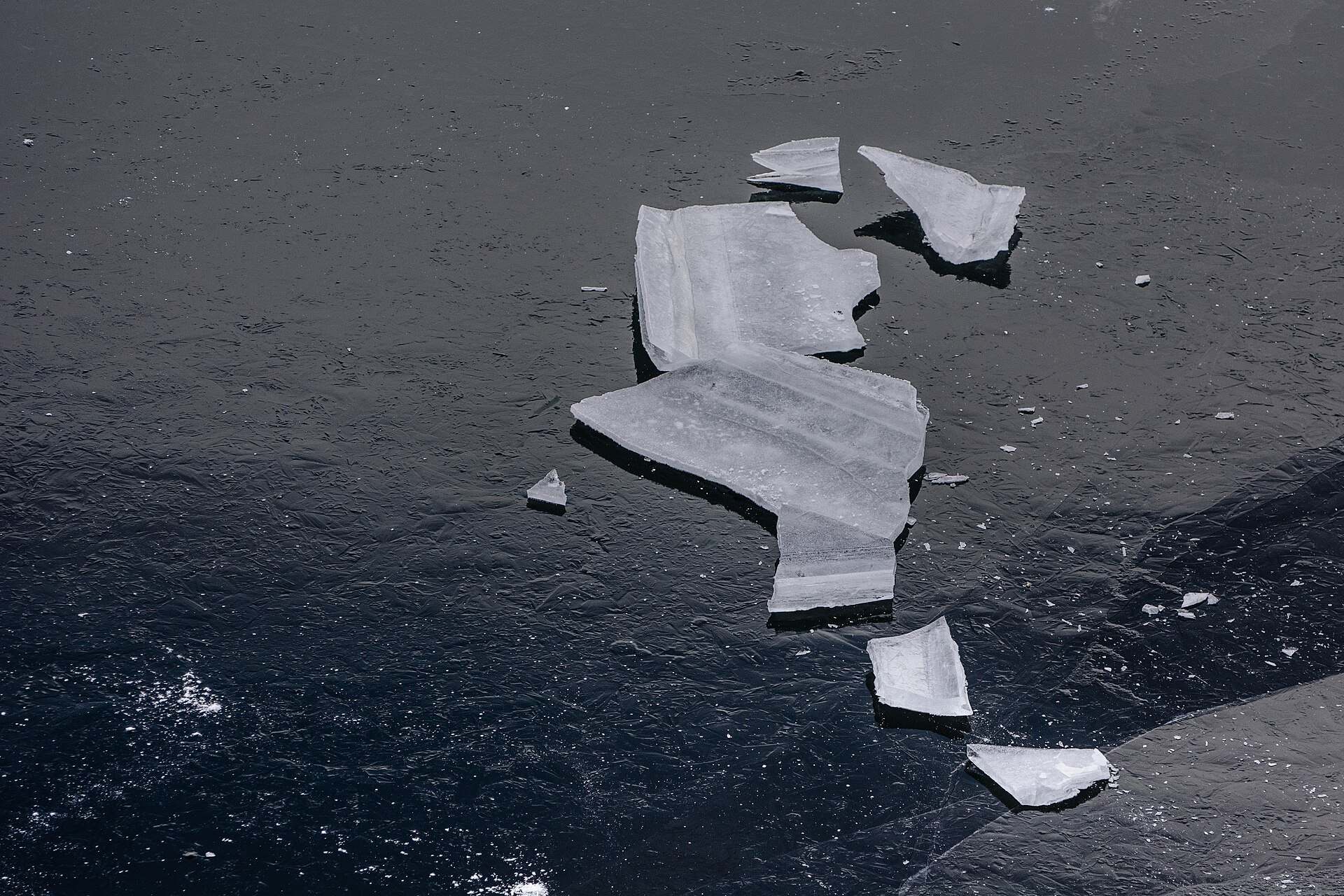Broken pieces of ice lying on a dark frozen lake, illustrating a Trevor L Taylor podcast episode on adaptation to habitual stress