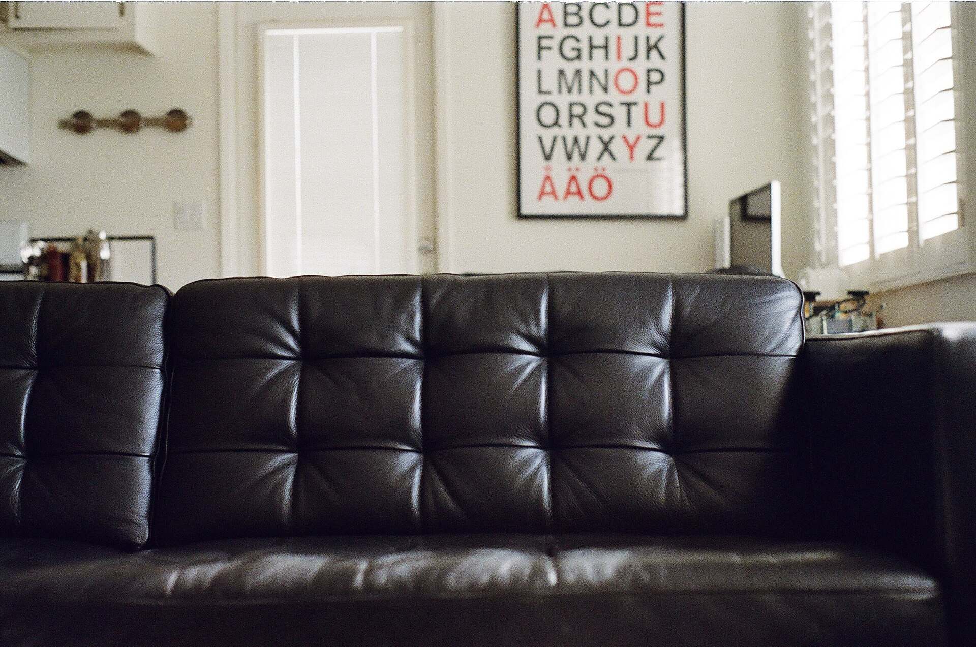 A black leather sofa in a bright living room, illustrating a Trevor L Taylor podcast episode on the comfort crisis