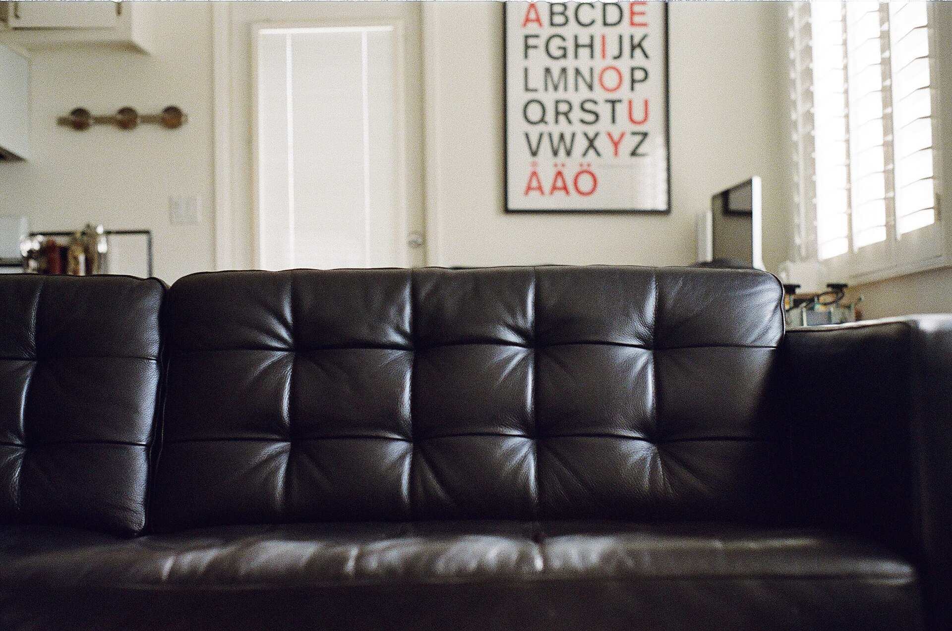 A black leather sofa in a bright living room, illustrating a Trevor L Taylor podcast episode on the comfort crisis