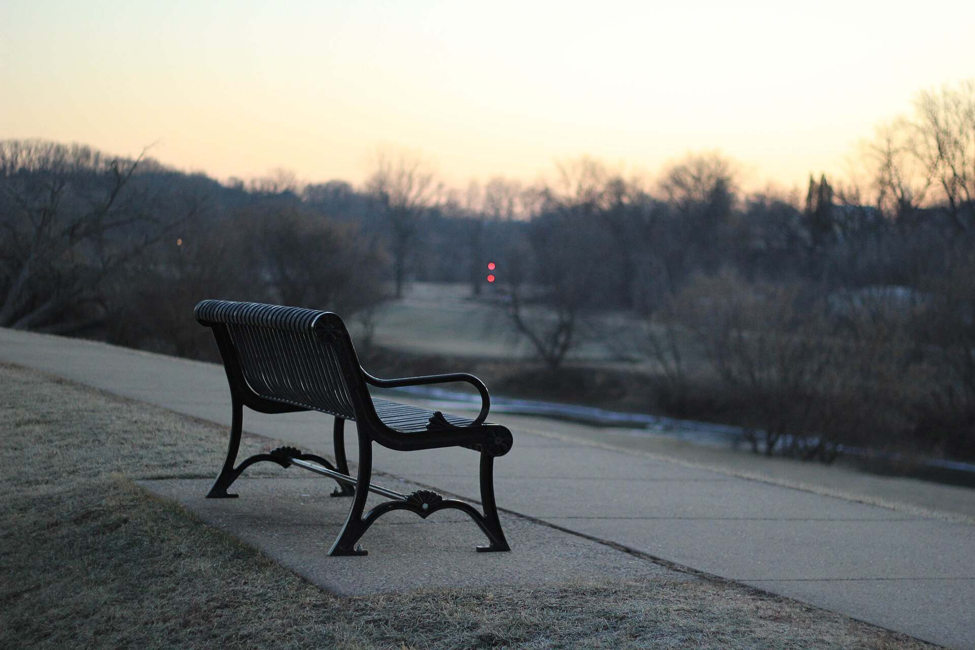 An empty park bench beside a path at dusk, illustrating a Trevor L Taylor podcast episode on rebuilding attraction after distance