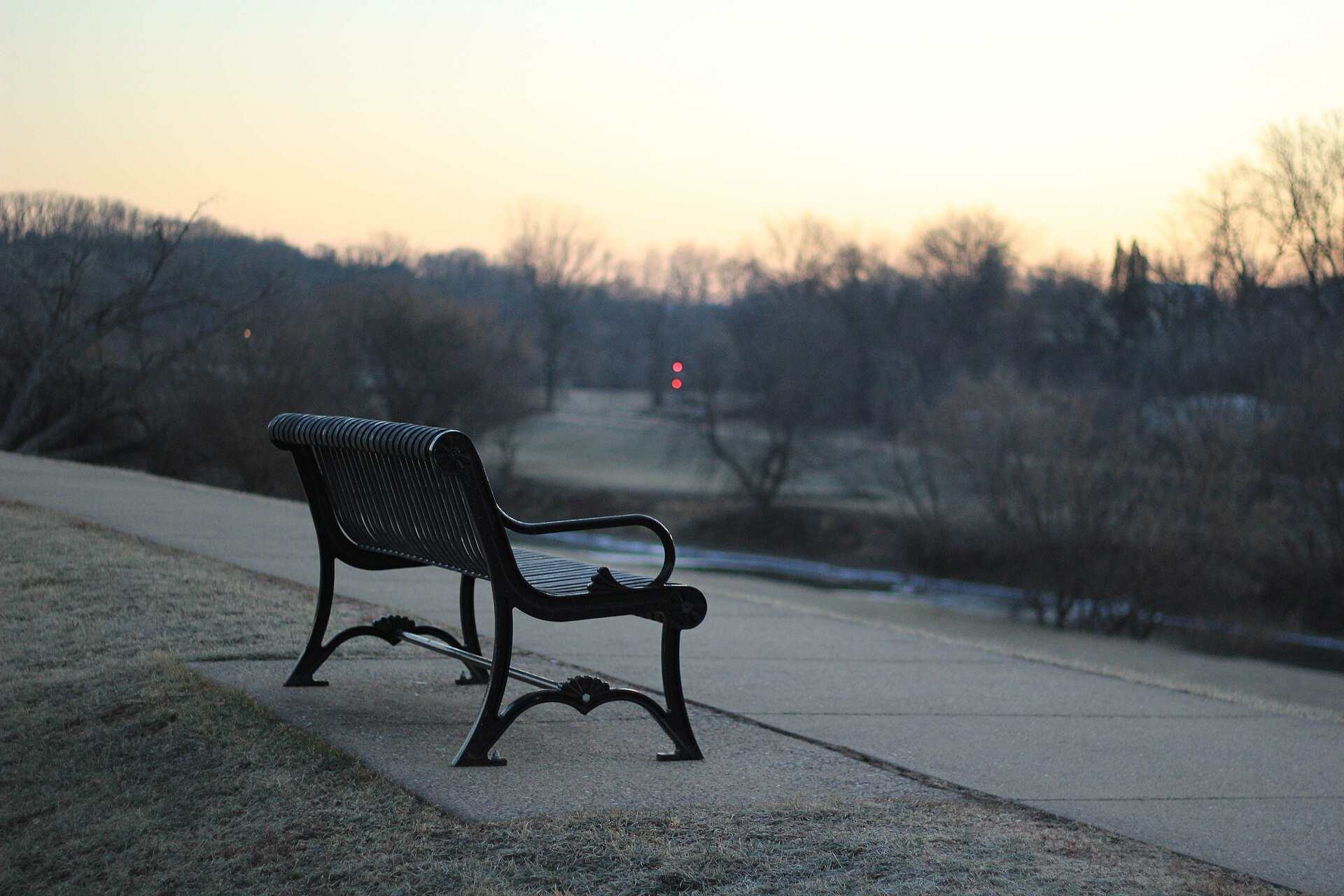 An empty park bench beside a path at dusk, illustrating a Trevor L Taylor podcast episode on rebuilding attraction after distance