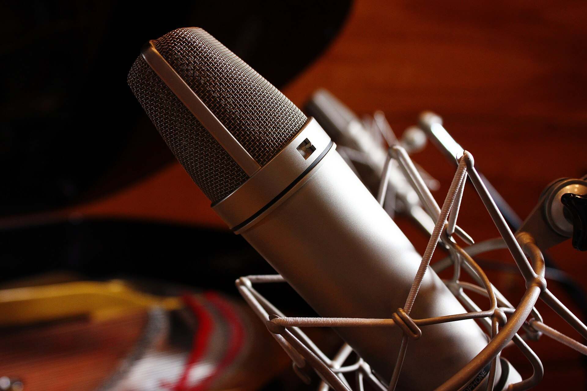 A silver Neumann condenser microphone in a shock mount inside a recording studio, from the Trevor L Taylor entry on long format shows