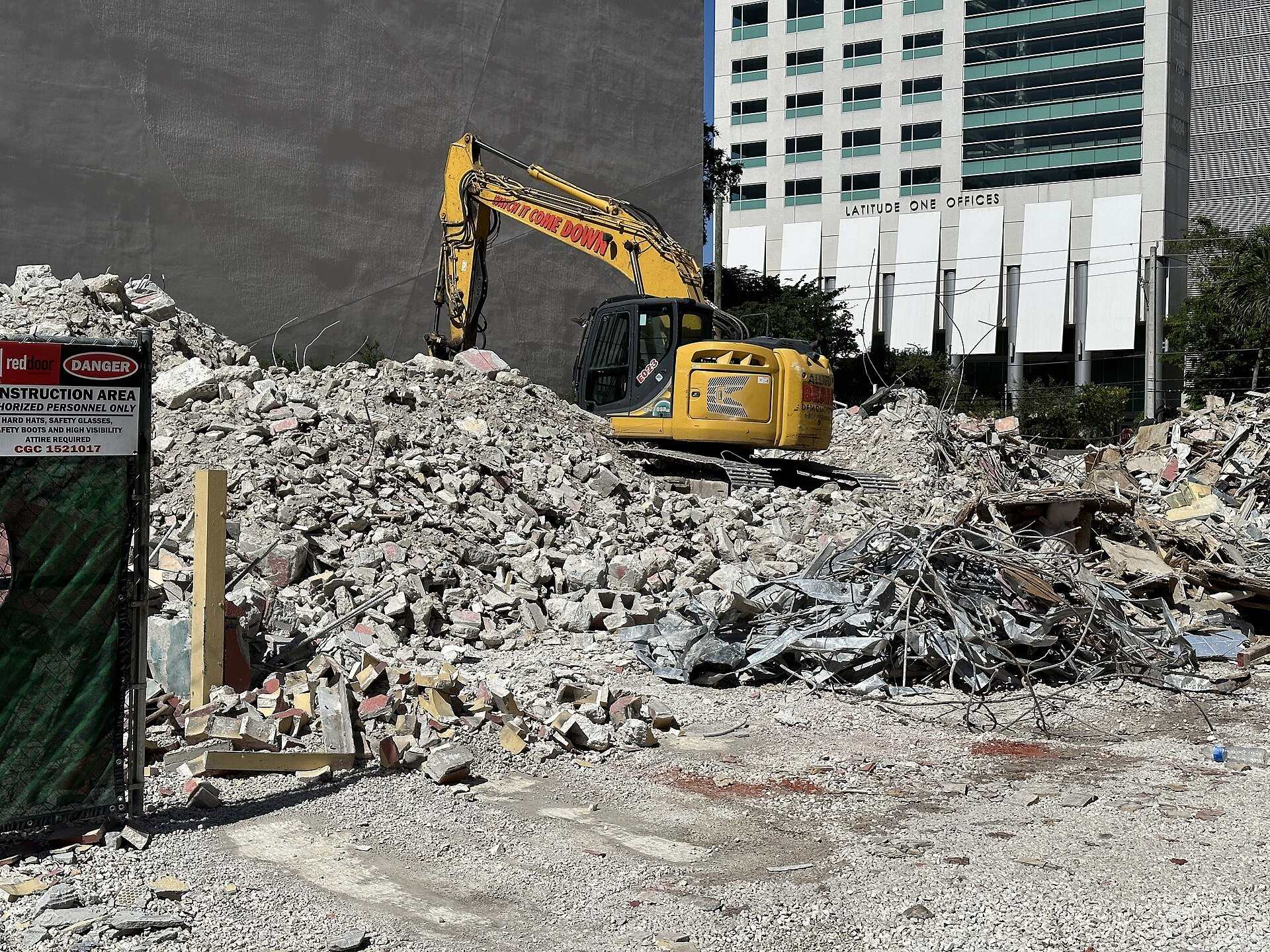 Excavator clearing rubble on a cleared Brickell lot beside office towers, from the Trevor L Taylor entry on why Miami land sells early