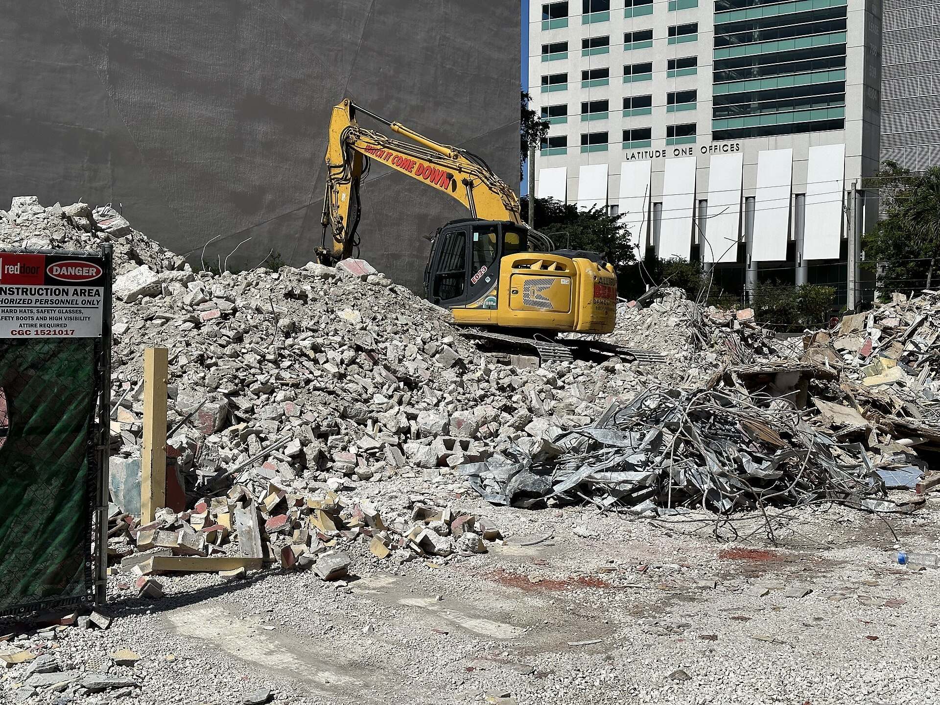 Excavator clearing rubble on a cleared Brickell lot beside office towers, from the Trevor L Taylor entry on why Miami land sells early