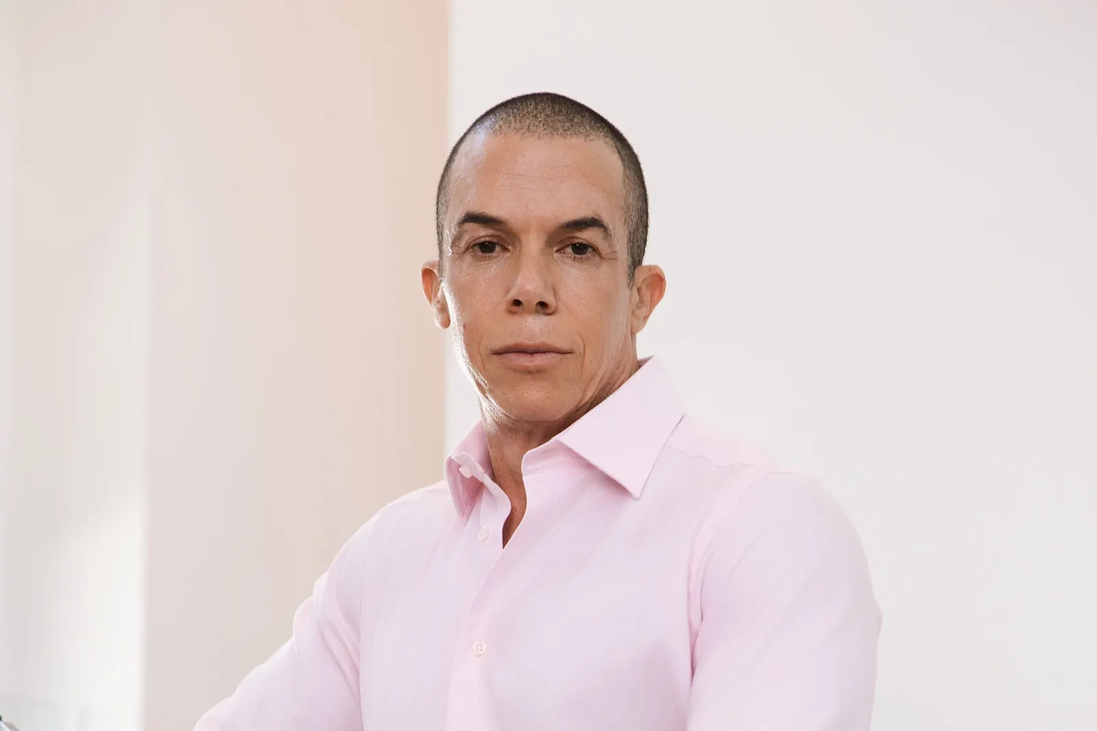 Trevor L Taylor standing at a stairway with a glass balustrade and a bright white wall behind him